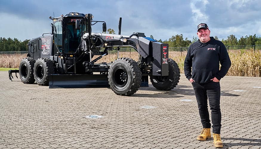 Tom Campbell standing in front of the new Cat Black Grader