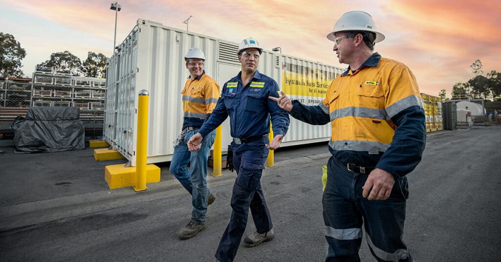 WesTrac reps walking with a Bengalla rep in front of hose solution